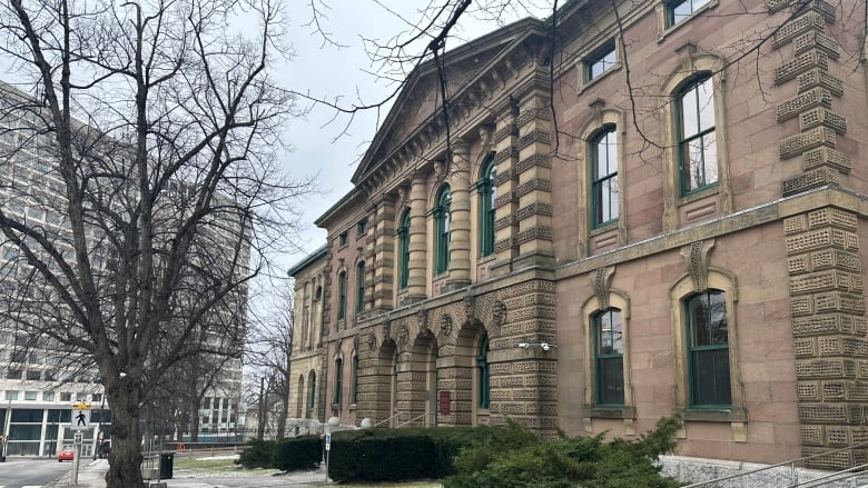 a historic court house building with the lawn partially covered in snow 