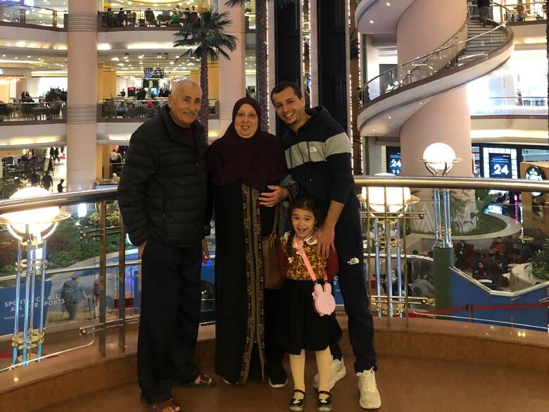 A portrait of two older people, an adult and a child posing in the atrium of a tall building. 