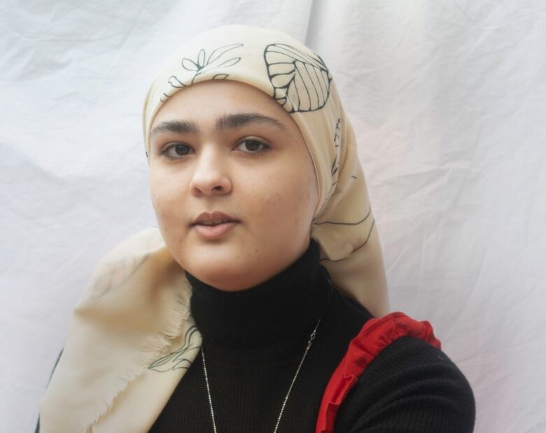 Portrait of a person in a black turtleneck and headscarf. 