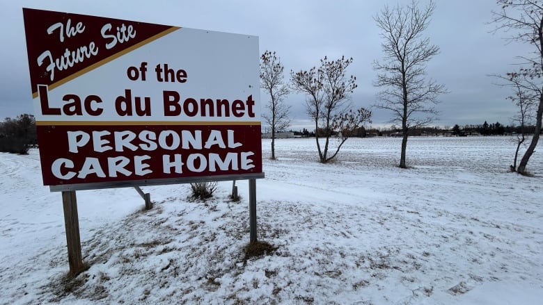 A sign that says future site of the Lac du Bonnet personal care home stands in a field partially covered with snow.