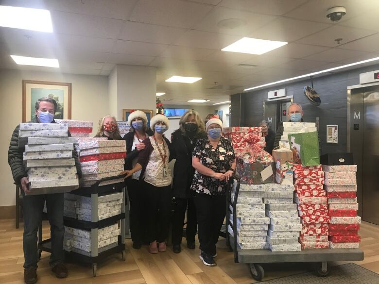 People wearing masks deliver piles of presents in boxes to a seniors home.