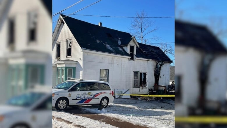 a police van parked in front of a partially burnt building with caution tape. 