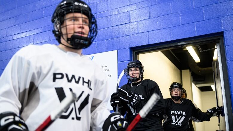 Hockey players walk through a hallway.