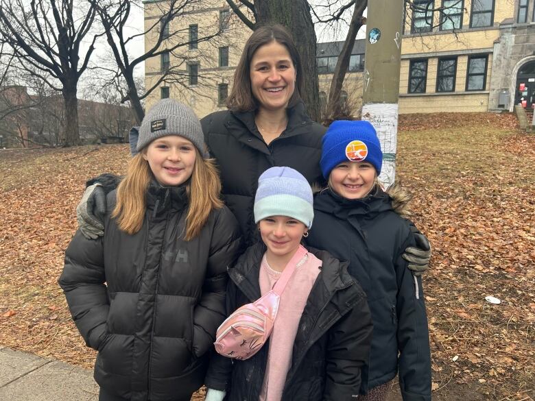 a brunette woman with her three daughters wearing winter coats smiling outside