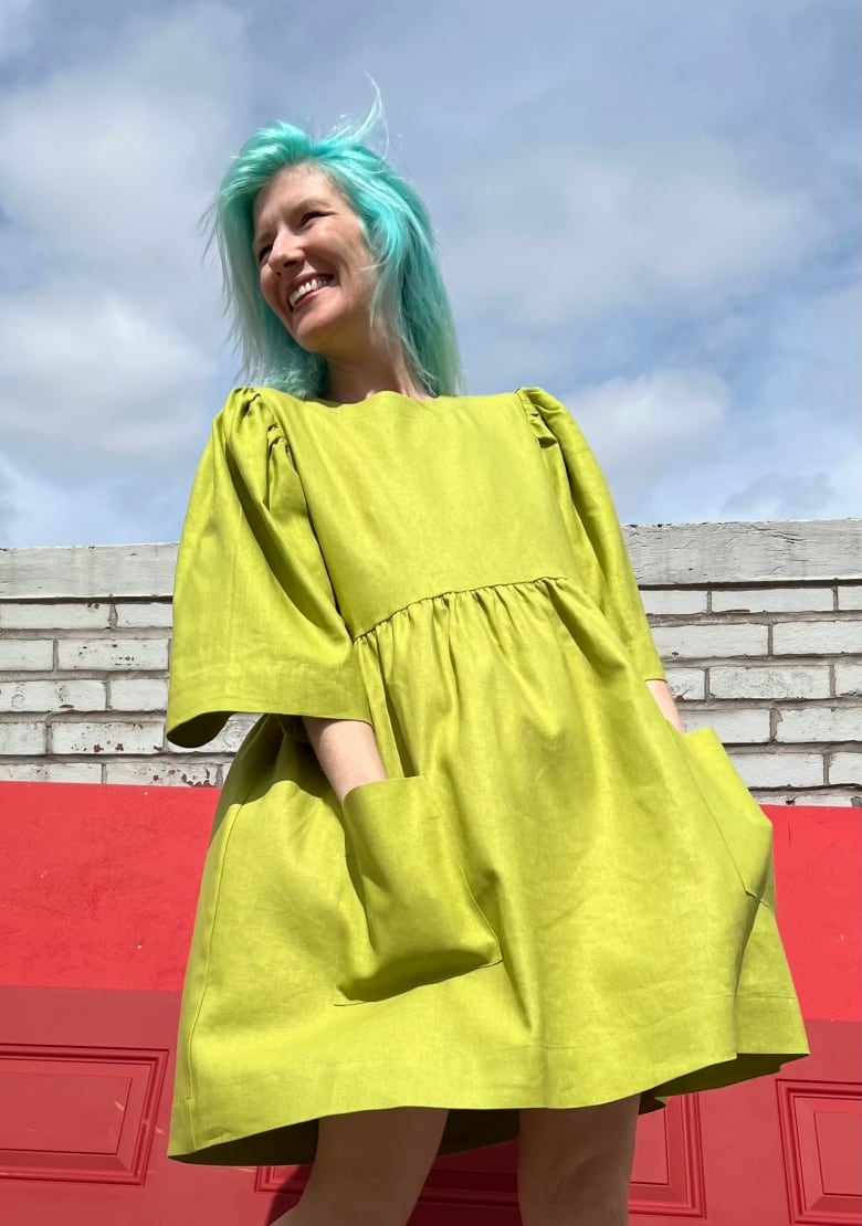 Woman wearing a green dress with her hands in her pocket. 