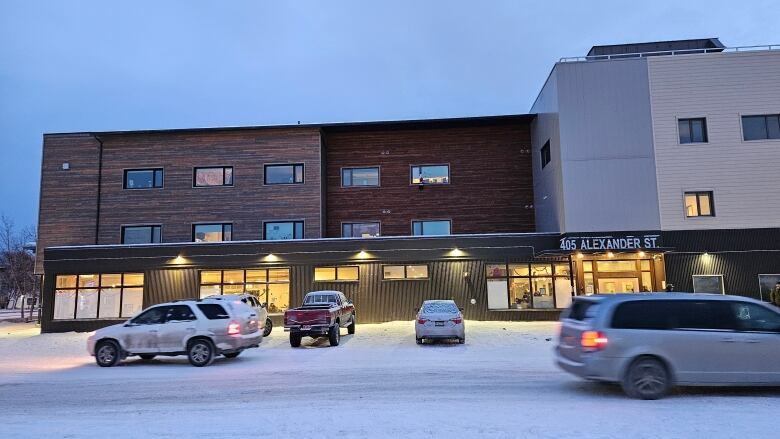 Photo of whitehorse emergency shelter, snow on the ground, two cars driving in opposite directions. 