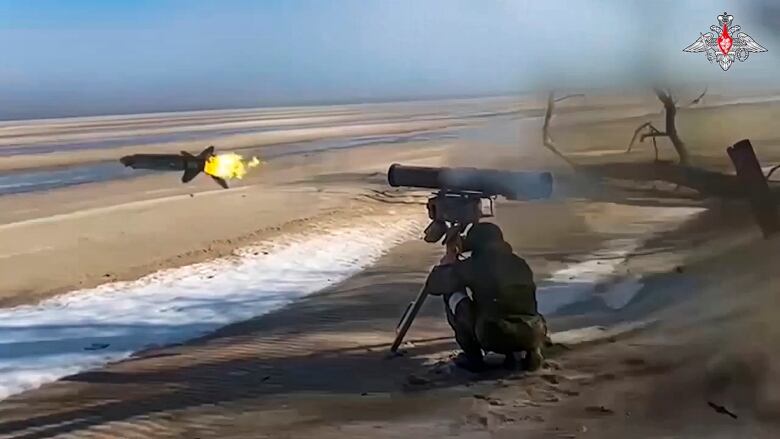 A soldier crouches down as he fires a missile.