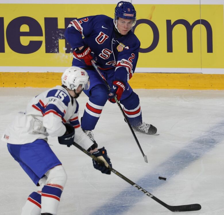 Two players skate toward the puck.