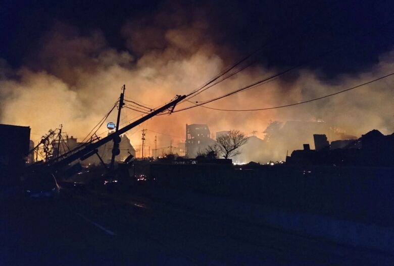 A fire burns among buildings during nighttime.