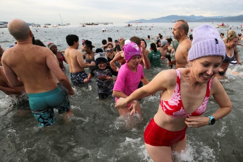 Lines of people run in and out of beachwater.