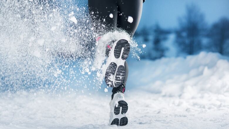 Image of a pair of feet wearing running shoes with the snow kicking up around them