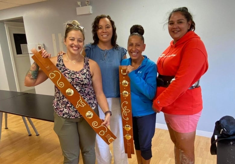 Four women hold belts.