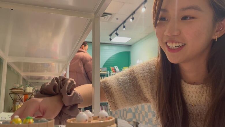 a woman smiles while arranging objects on a shelf.