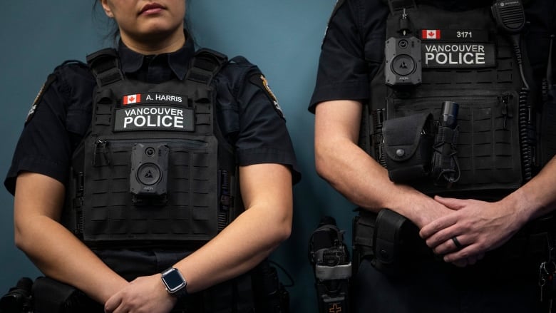 Two uniformed Vancouver police officers are shown from the neck down, with cameras attached to the fronts of their tactical vests.