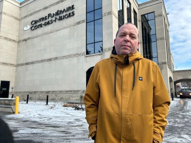 a man in a yellow coat posing in front of the Cote-de-neiges funeral home.