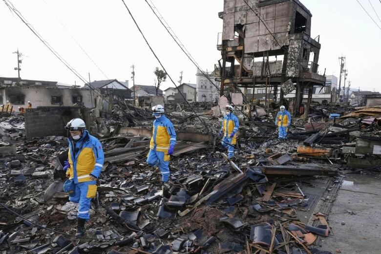 Police officers search for survivors in the wake of a deadly quake and subsequent fire in Wajima, Japan.