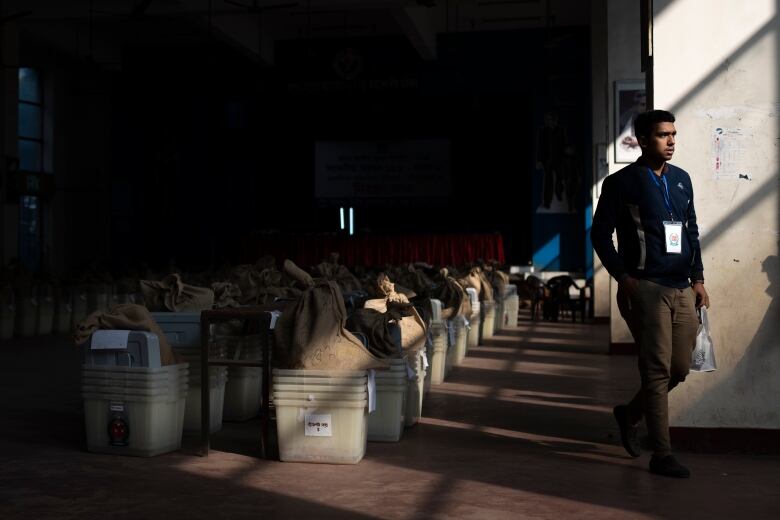 An election official walks past ballot boxes and election-related materials, at an auditorium in Dhaka, Bangladesh.