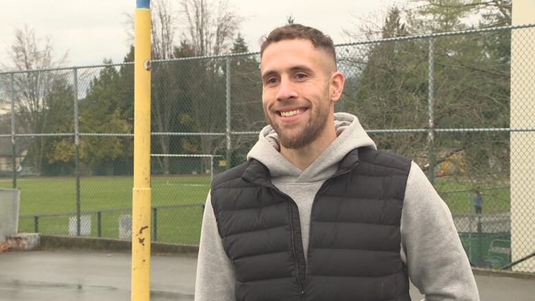 A man smiles in a basketball court.