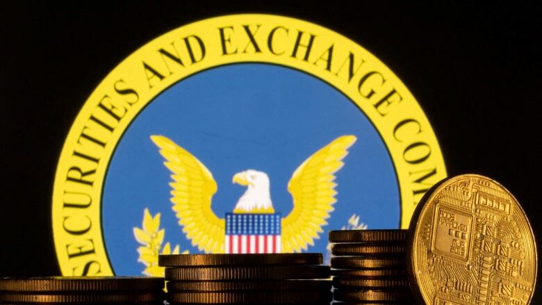 A representation of cryptocurrency is piled in front of a U.S. Securities and Exchange Commission logo.