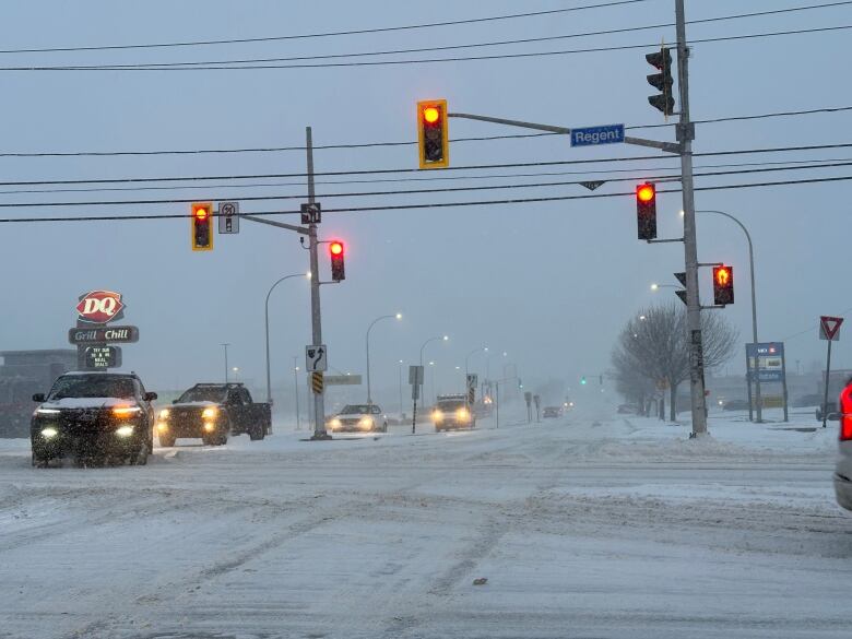 A snow intersection with cars driving through it