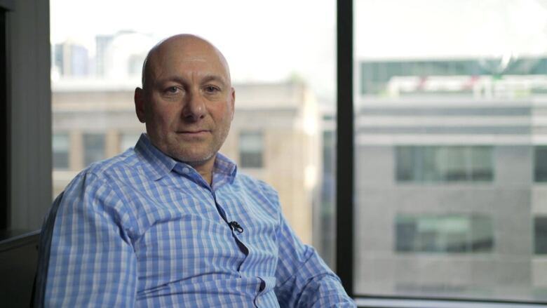 A man sitting near a window looking into the camera. 