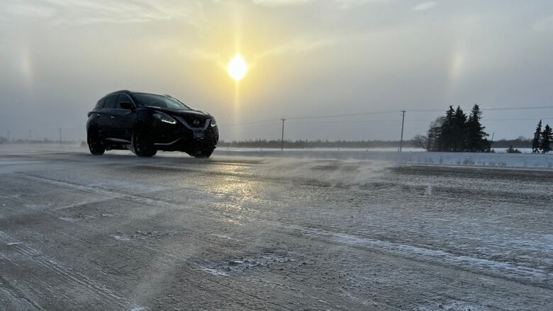 A vehicle drives on a snowy highway.