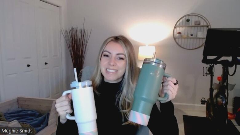 Meghie Smids holds up two Stanley water bottles. 