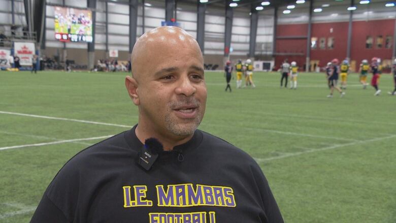 Football coach standing infront of football field