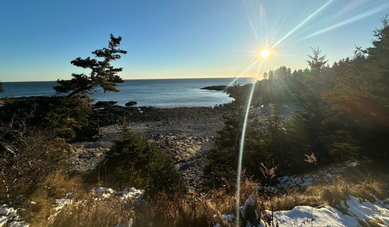 Rocky waterfront property with the sun setting over the water. 