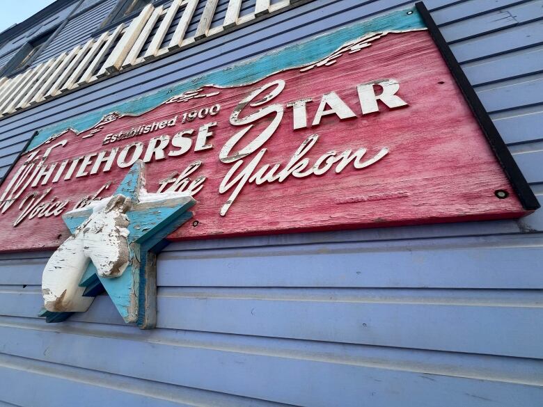 A weathered sign on the side of a building reads, 'Whitehorse Star: Voice of the Yukon.'