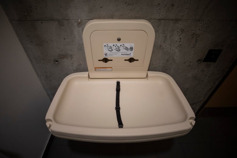 A baby change table is folded up against a concrete wall.