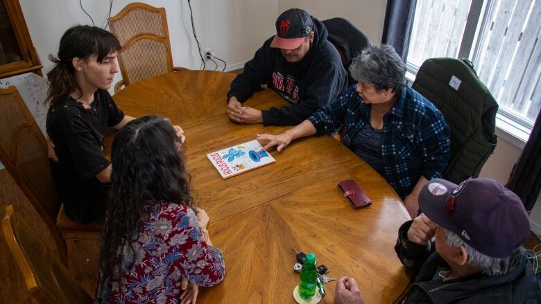 A group of people look at a book on a table.