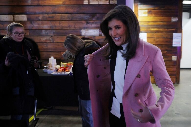 Haley, in pastel winter coat, smiling and walking into a room