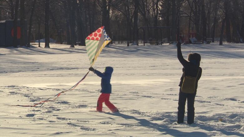 An adult and child attempt to fly a kite.