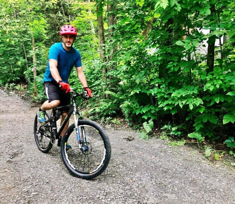 A man pictued riding a bicycle on a dirt path in a forest 