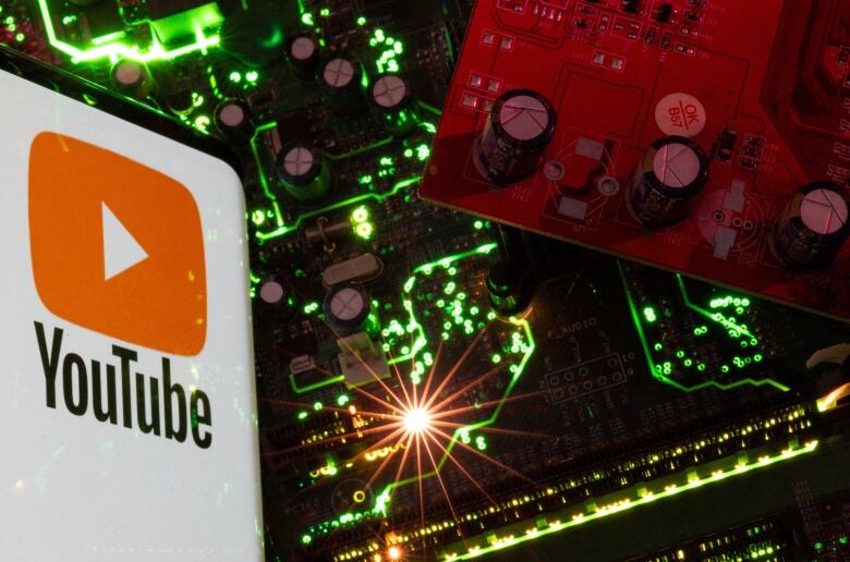 A smartphone with a displayed YouTube logo is placed on a computer motherboard