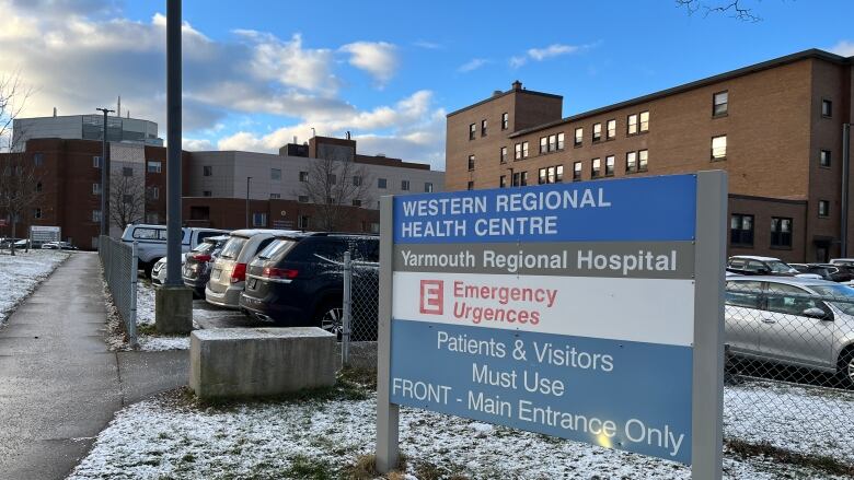 A sign for a hospital in the foreground, with the hospital in the background.