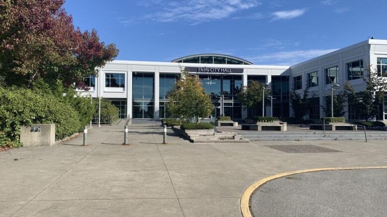 A building is pictured with a signage on the front facade that reads, 'Delta City Hall'.