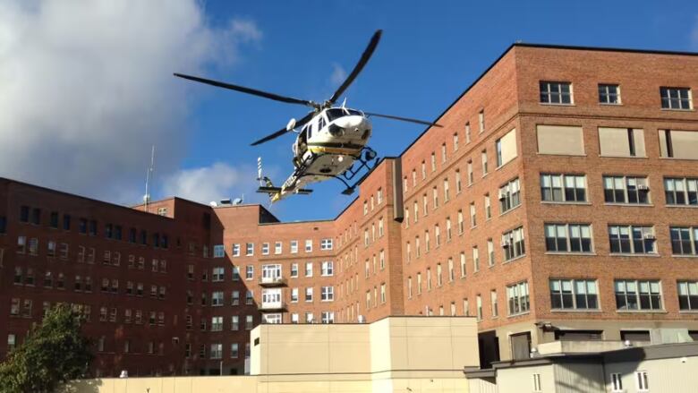 A helicopter hovers over a brown brick hospital.