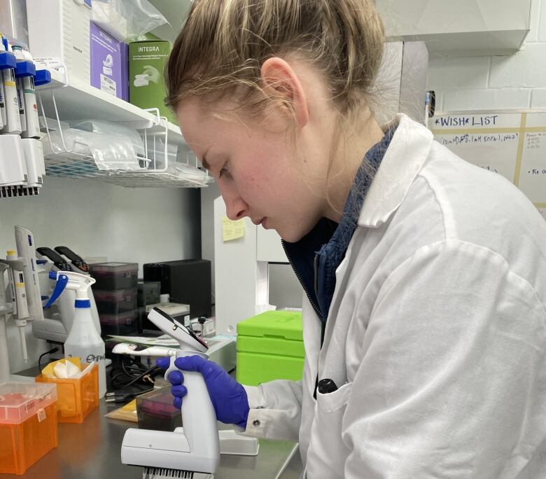 A woman in a lab coat analyzes materials in a scientific setting.