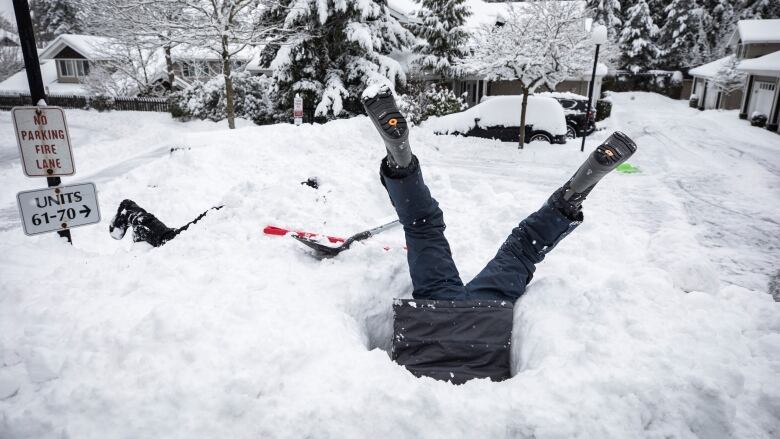 A child's legs are visible sticking out of a snowpile.