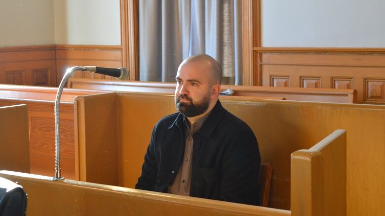 A man looks ahead calmly in a wooden court dock