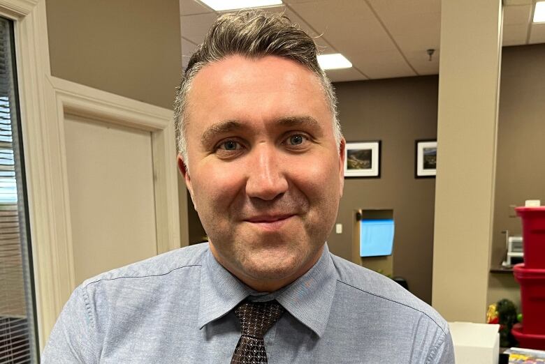 A portrait style photo of Chris Forward, wearing a shirt and tie.