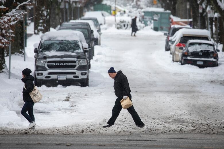 A man crosses the street after a period of heavy snowfall.