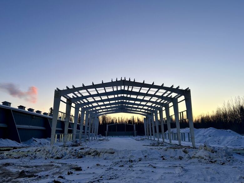 The frame of a building is seen on a snow-covered building site.