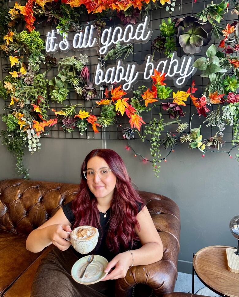 A woman sitting in a cafe holding up a coffee