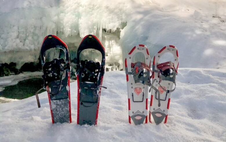 Two pairs of snowshoes stuck into the snow.