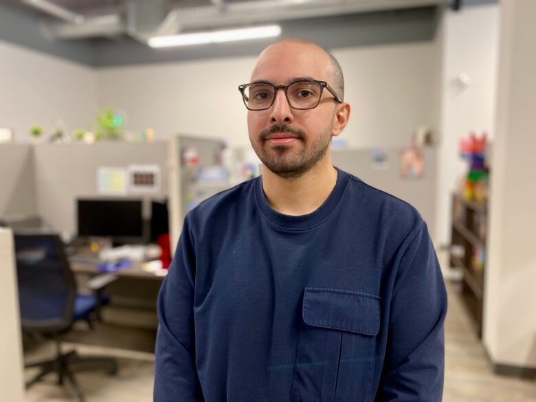 A spectacled bald man smiling.