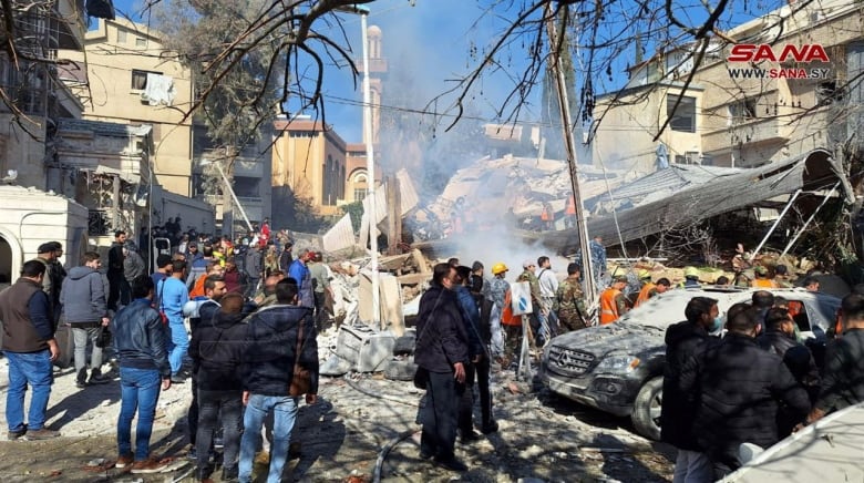 A crowd gathers near a building destroyed by an Israeli strike in Damascus.