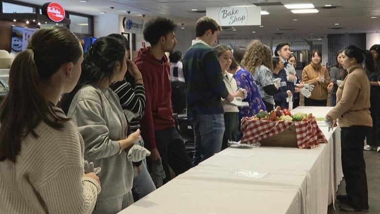 a group of people stand around a table.